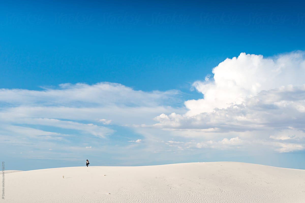Man Approaching From Horizon Carrying Camping and Photography Gear in White Sands National Monument New Mexico