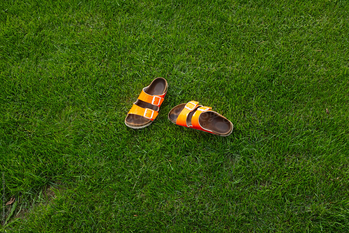 Neon orange sandals laying on green grass