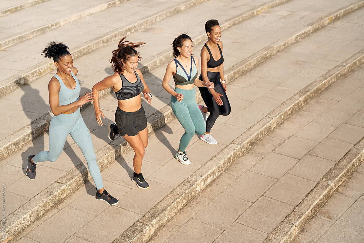 Company of fit women running during training in city