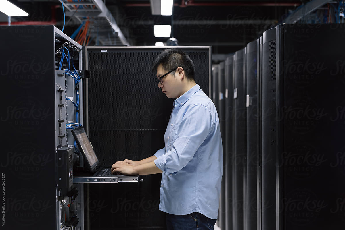 Server room technician using computer in server room