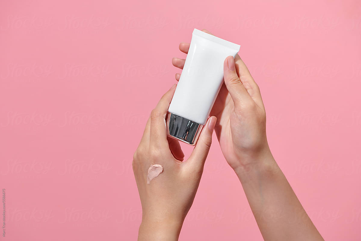 Woman holding makeup tube, testing creamy foundation