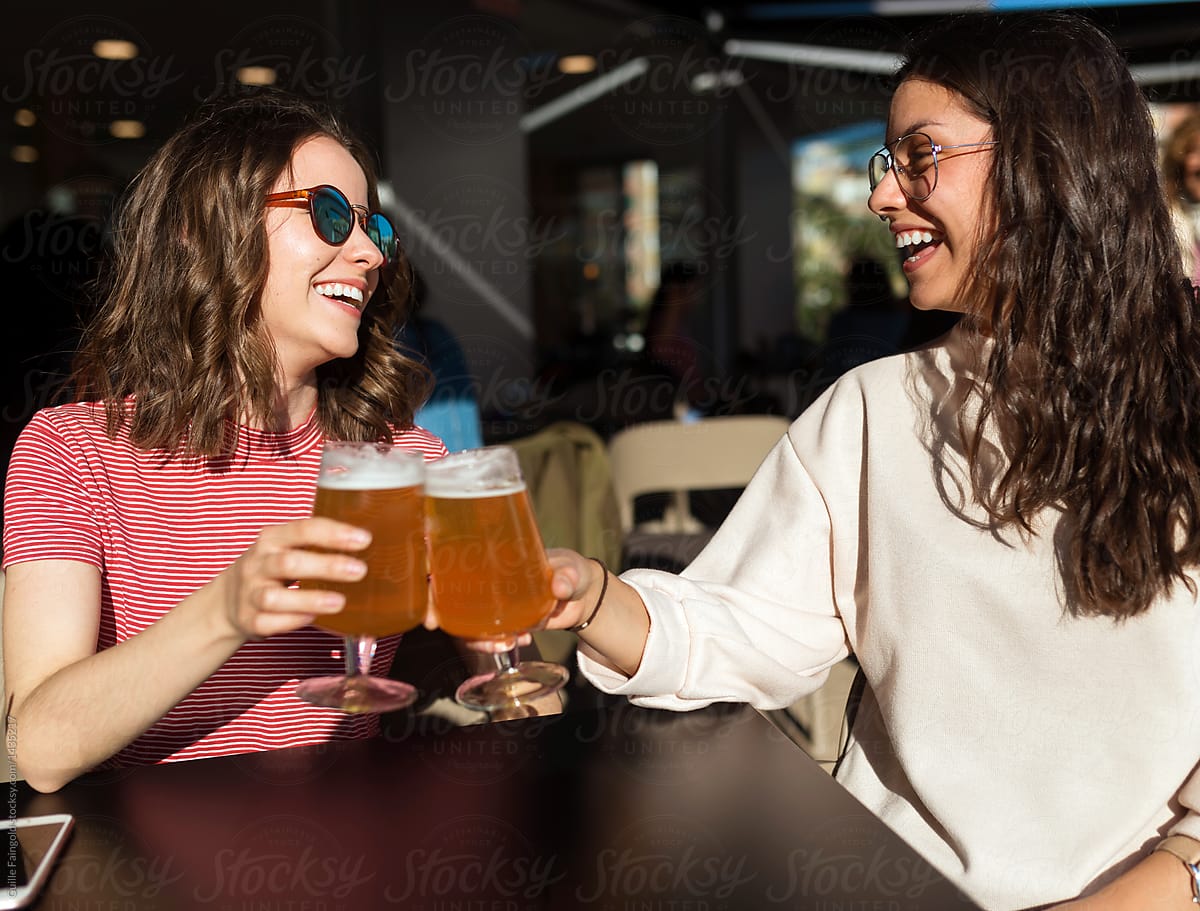 Women clinking beer in cafe