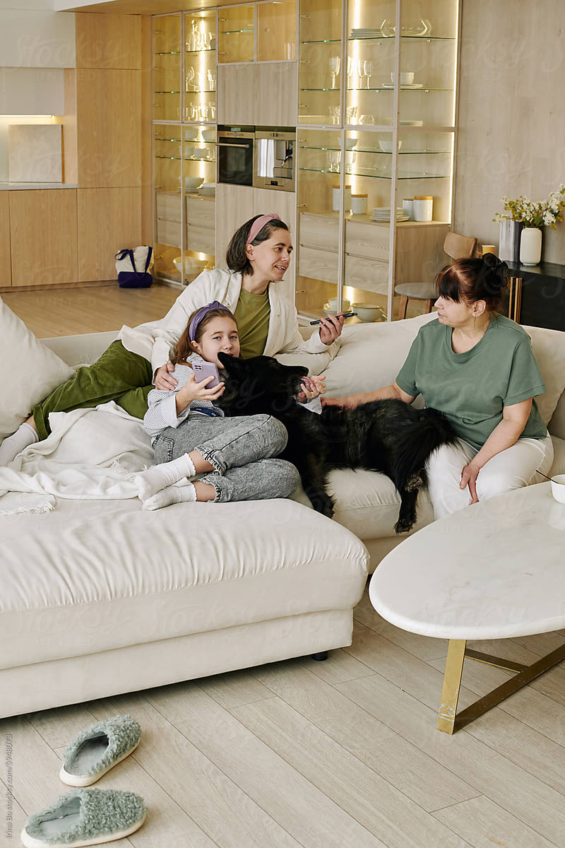 A family of three is snuggled up on a blanket with their black dog