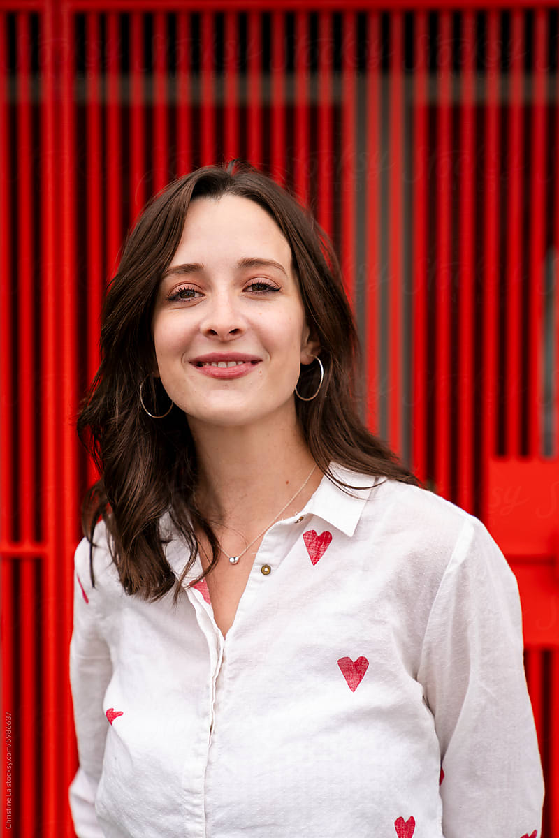 Portrait of smiling woman wearing hearts with red fence background