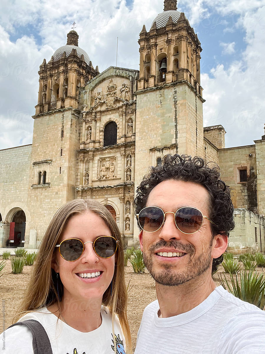 A smiling couple takes a selfie in front of Santo Domingo Oaxaca