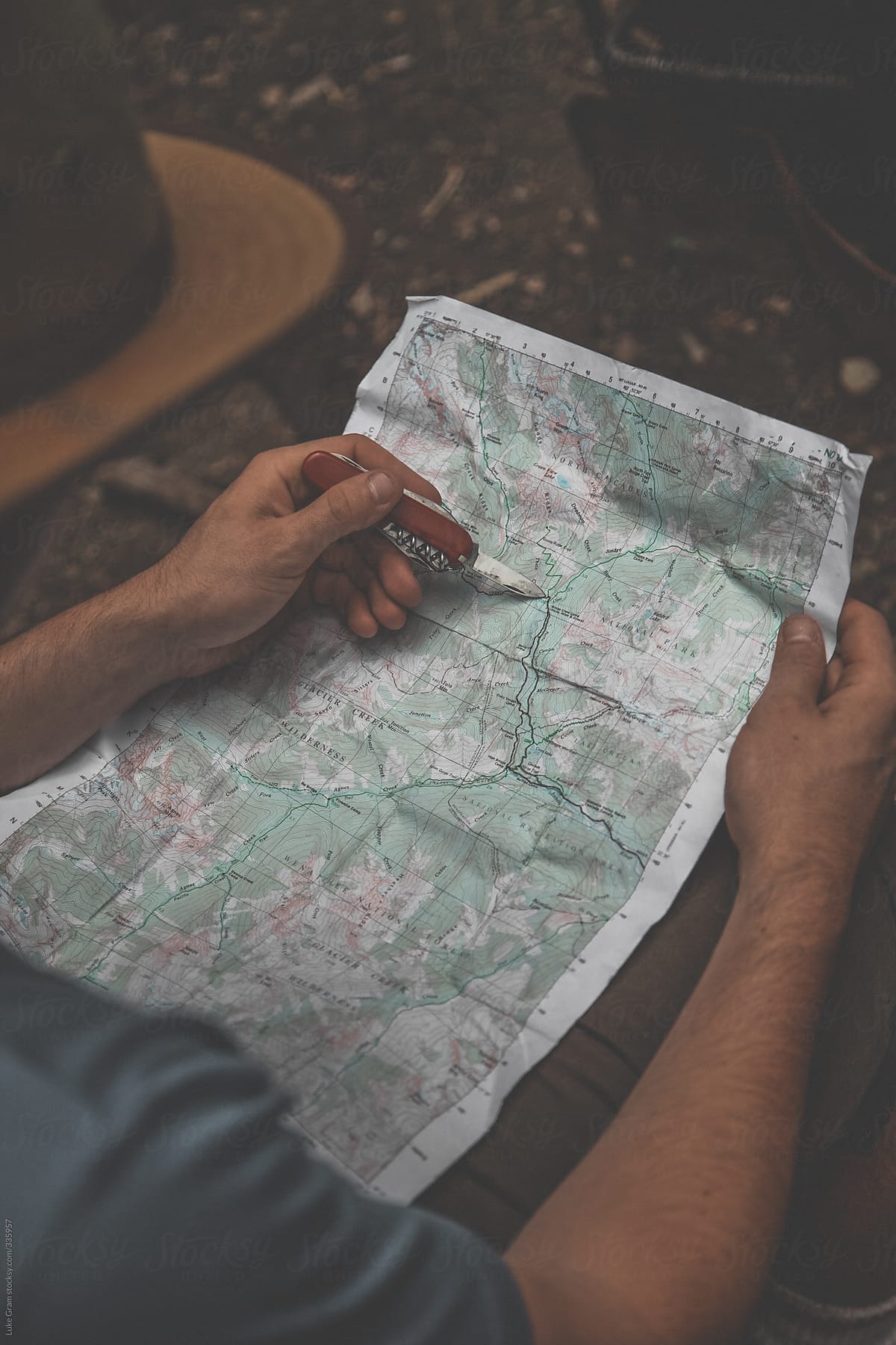 Man plotting a hiking route with a map and knife