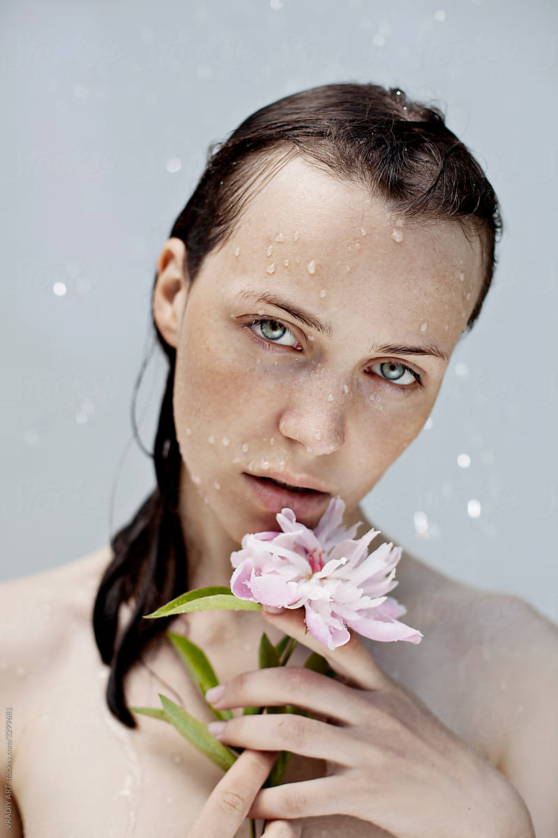 Vulnerable sensual woman standing under water with flower