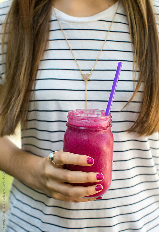 Female holding a homemade purple smoothie in a mason jar
