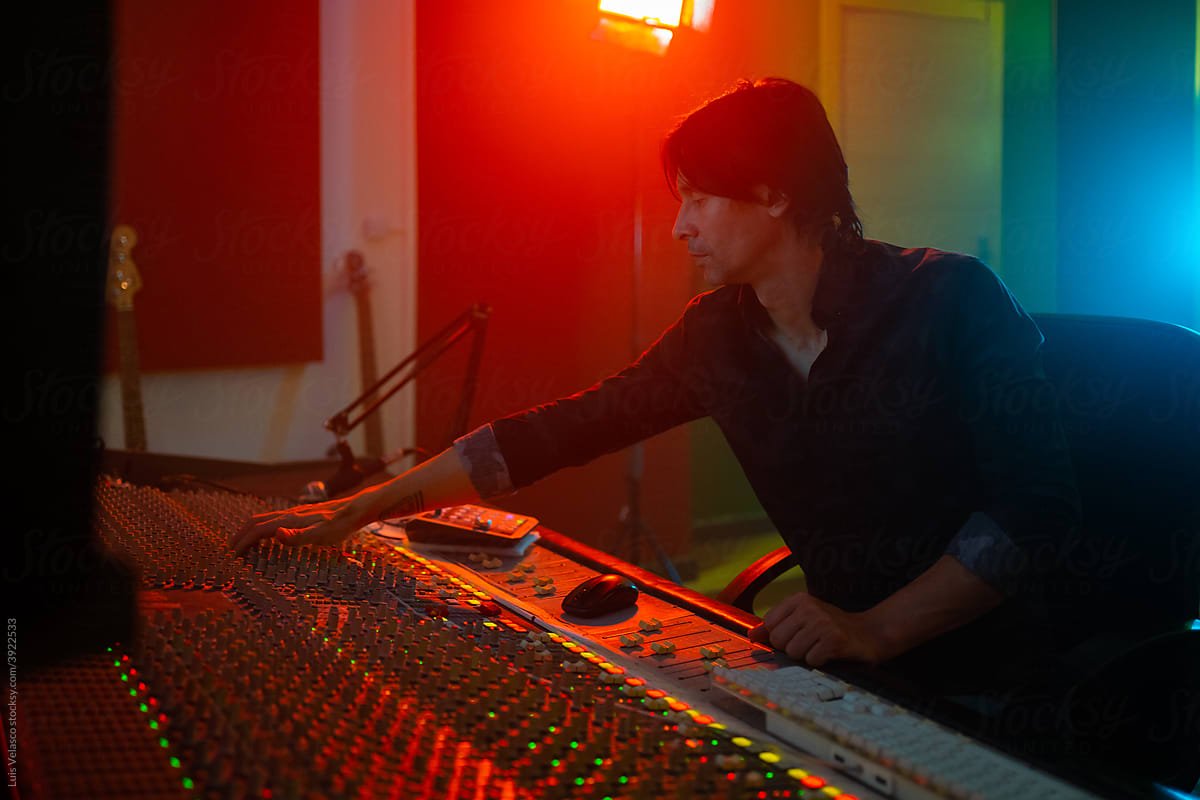 Male Music Producer Working In The Studio Using A Mixer Sound Desk.