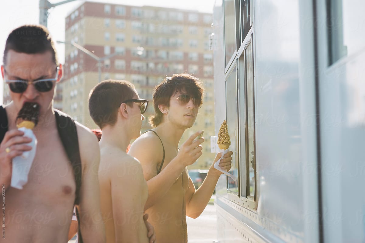 Young Men Friends Lining Up to Buy Soft Serve Ice Cream from Food Truck in Hot Sunny Summer in Rockaway Beach