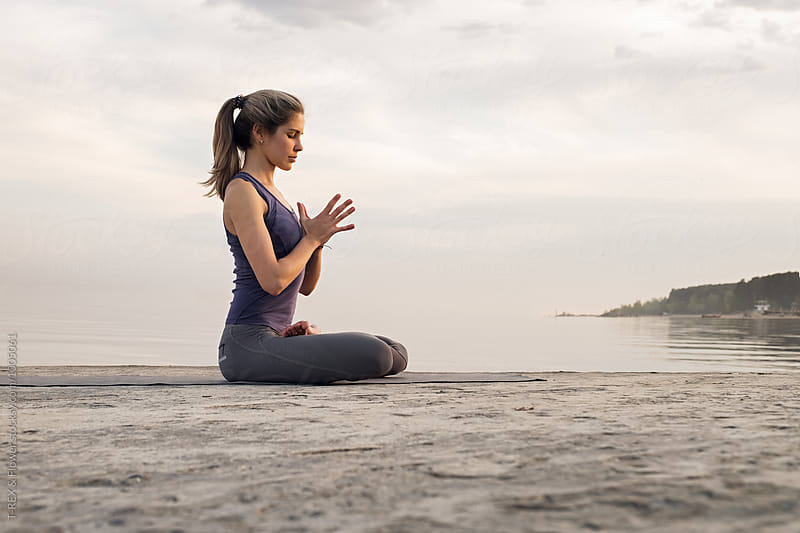 Blonde woman practicing yoga at waterfront