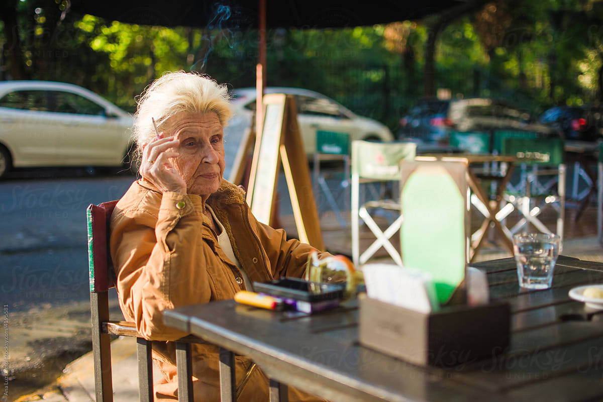 Senior woman smoking and having coffee outdoors