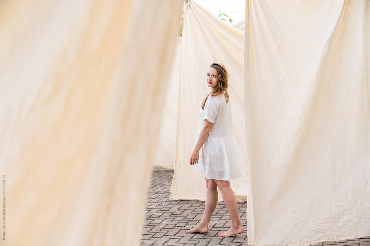 Woman Walking In Background Of Hanged Bed Linen