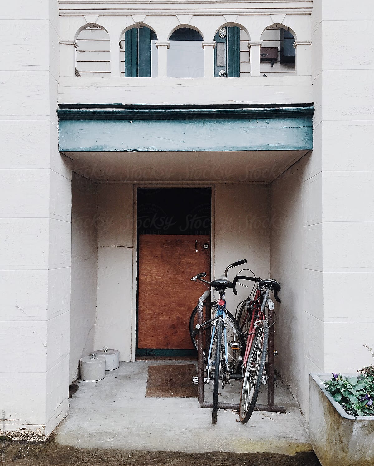 Two bikes leaning against a wall by a brown door