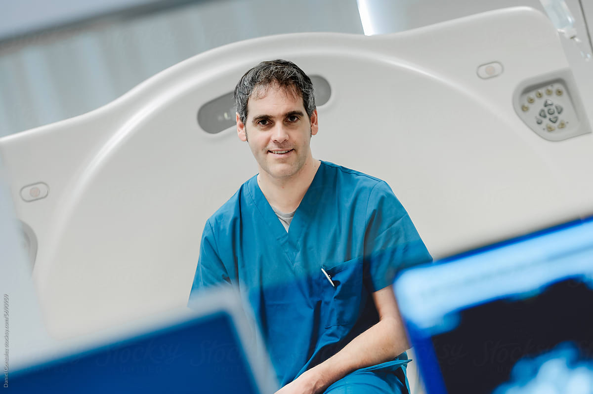Happy adult vet doctor sitting on scanner near monitors