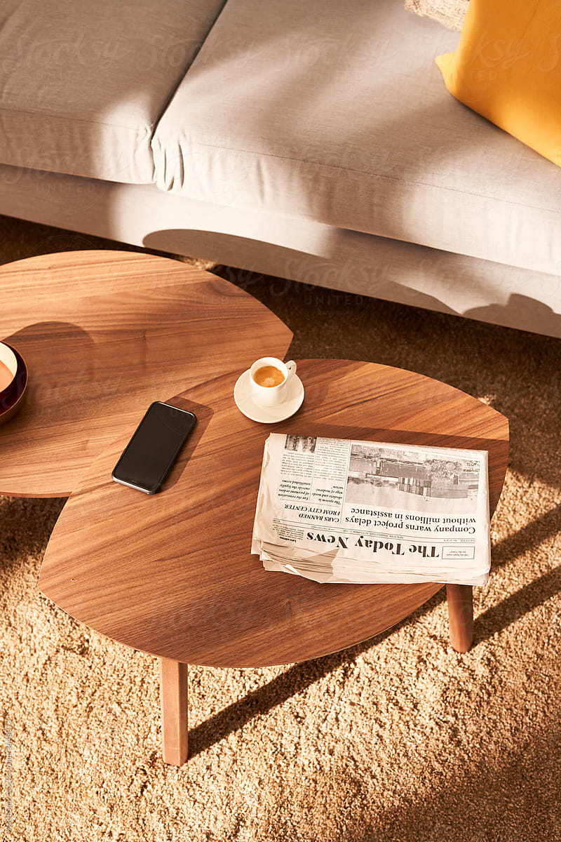 Coffee table with newspaper and smartphone near sofa