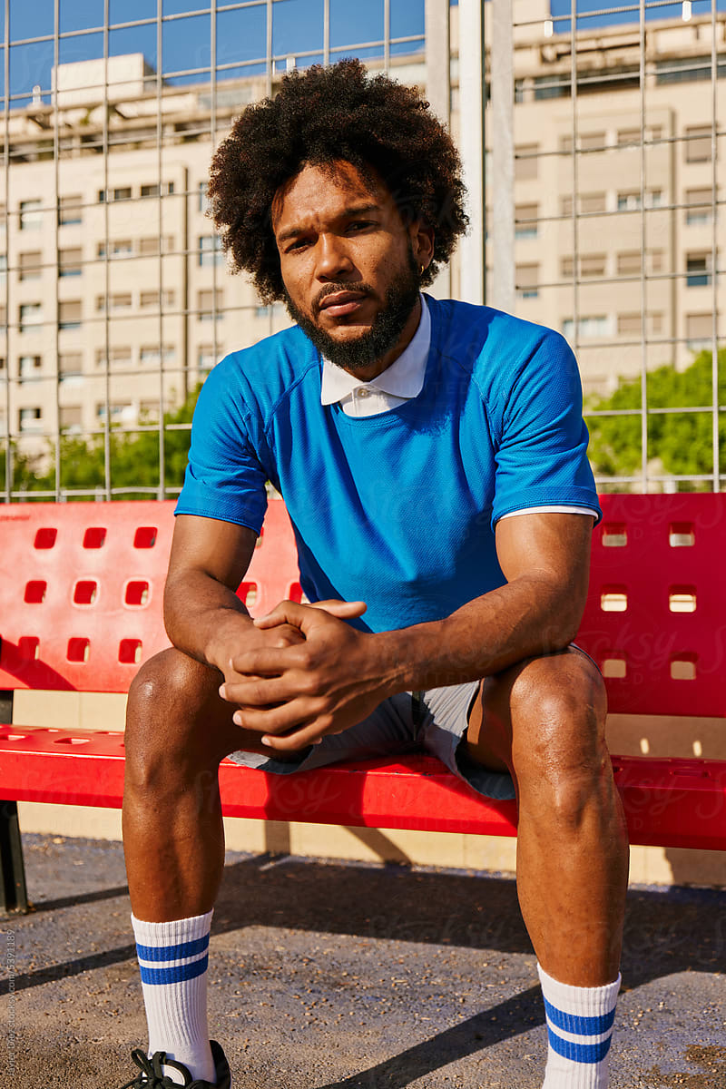 Confident football player sitting on bench
