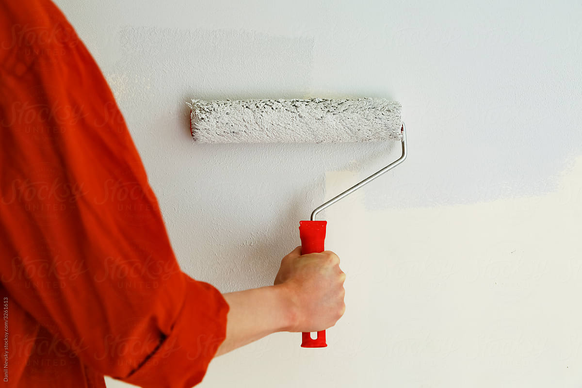 Anonymous woman painting wall in room