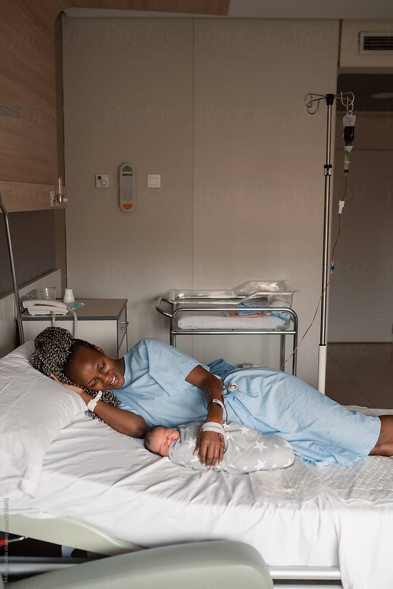Loving African mom with infant resting on hospital bed