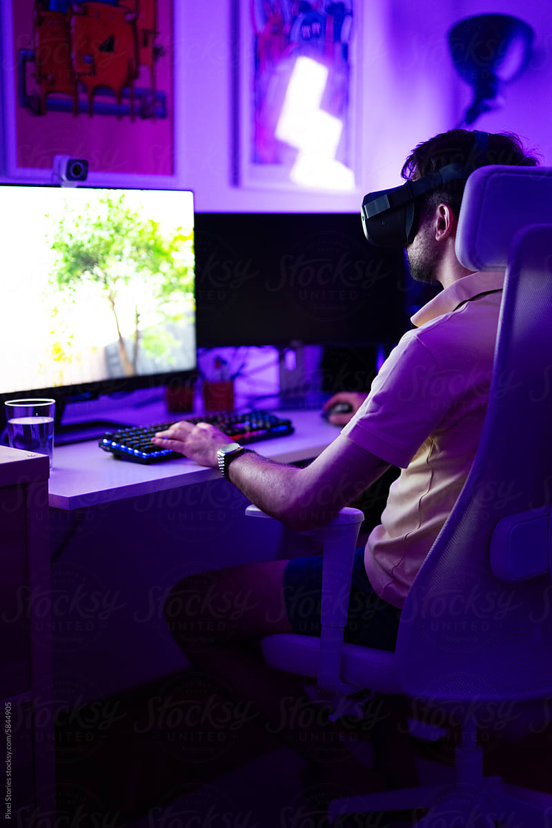 Young adult gamer playing using VR headset on computer PC
