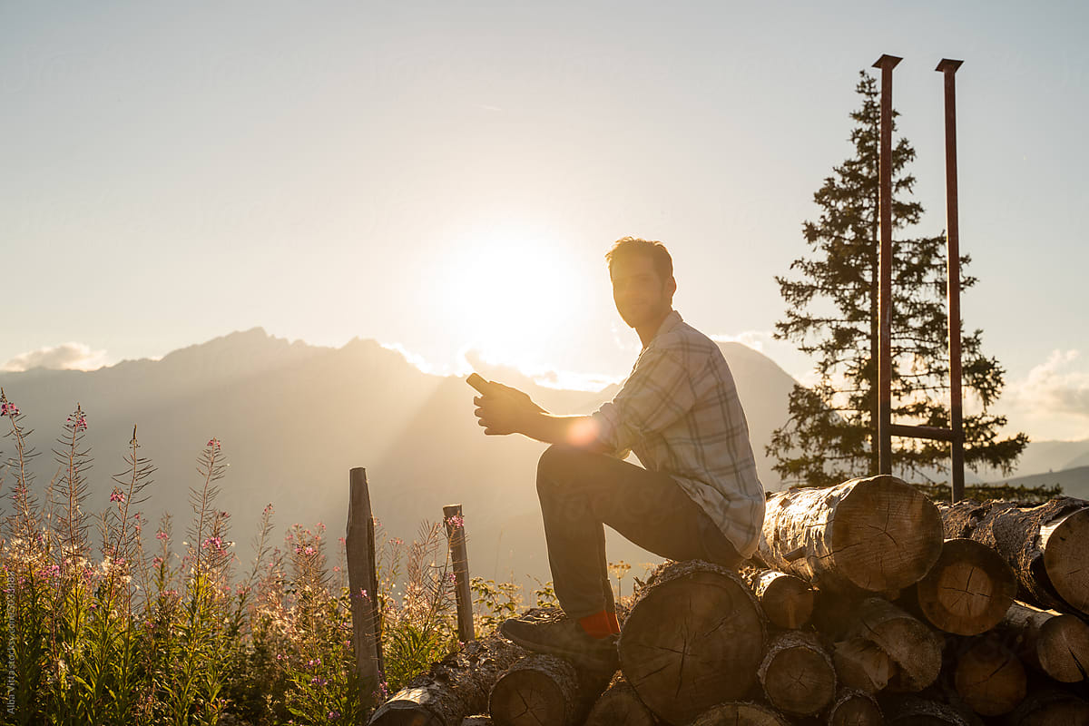 Happy man in the mountain at sunset with phone