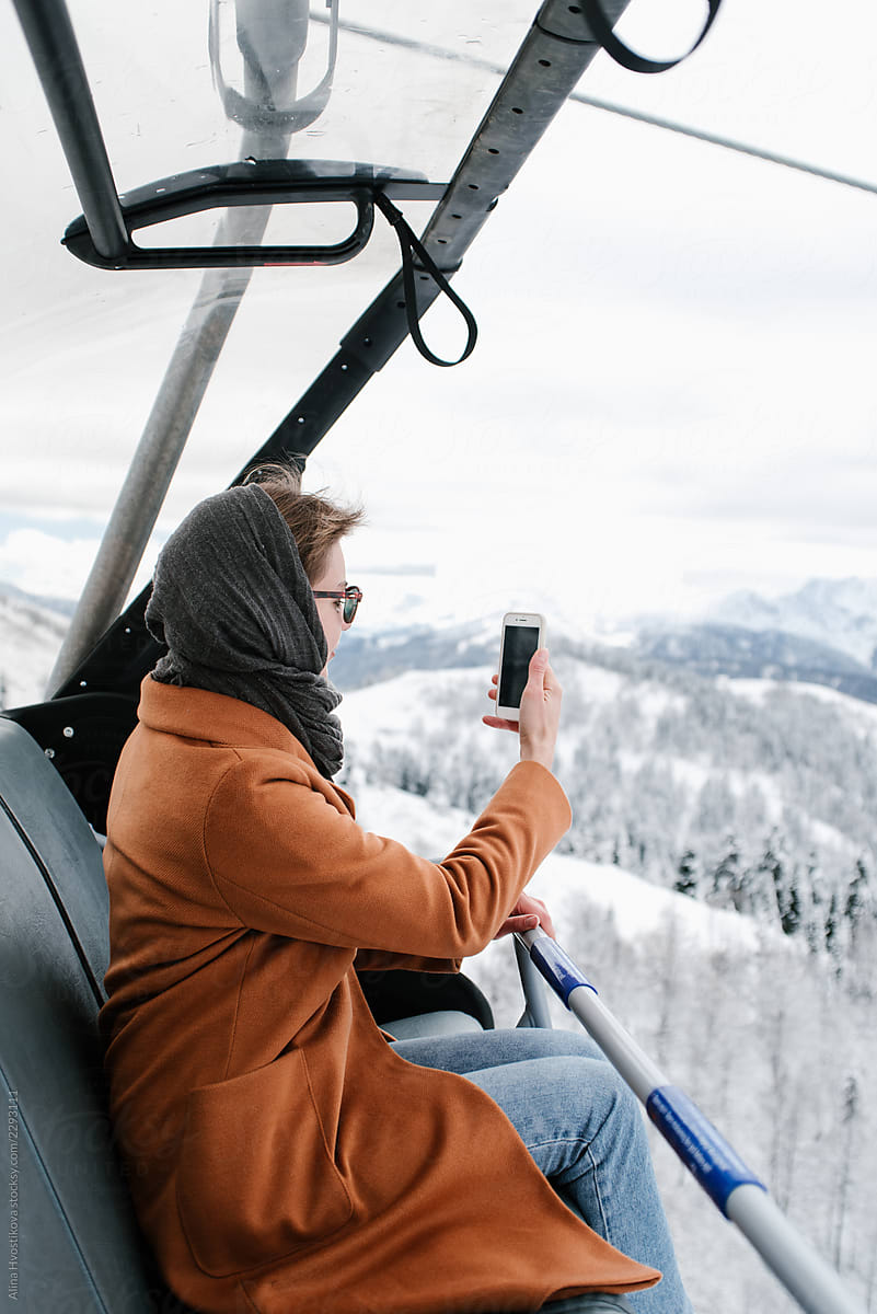 Woman taking photo of mountains from chairlift