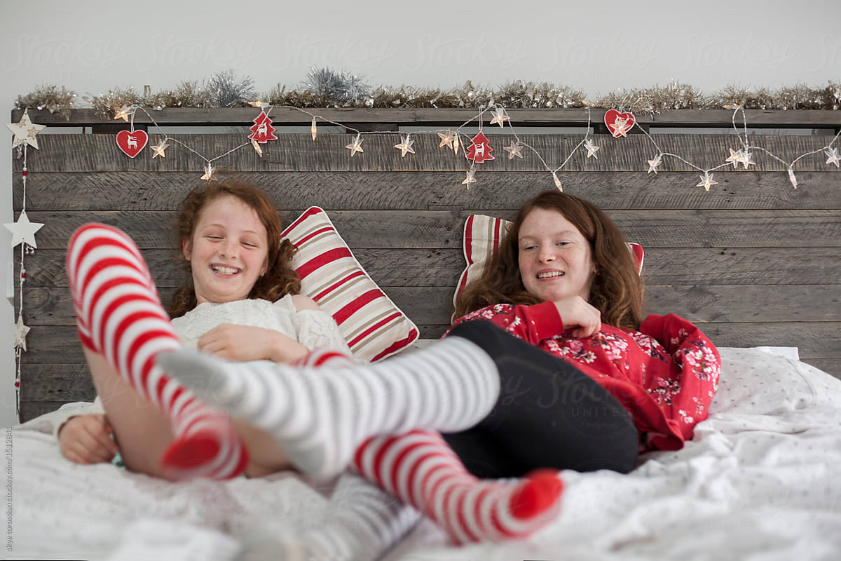 Sisters playing on bed with christmas decorations