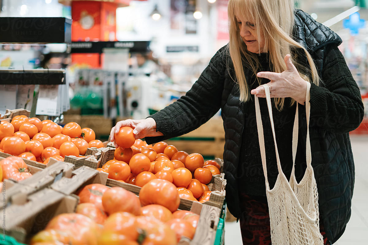 Female customer choosing tomatoes in supermarket