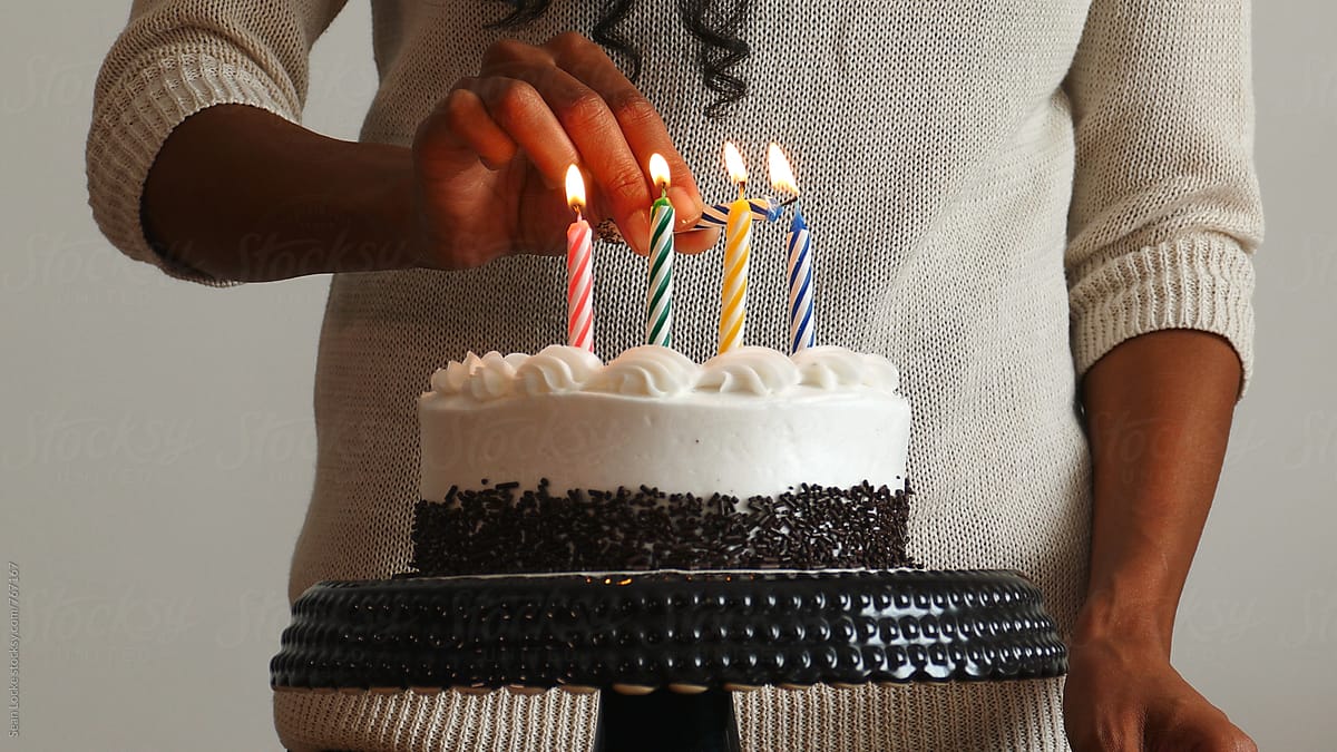 Woman Lighting Candles On Birthday Cake