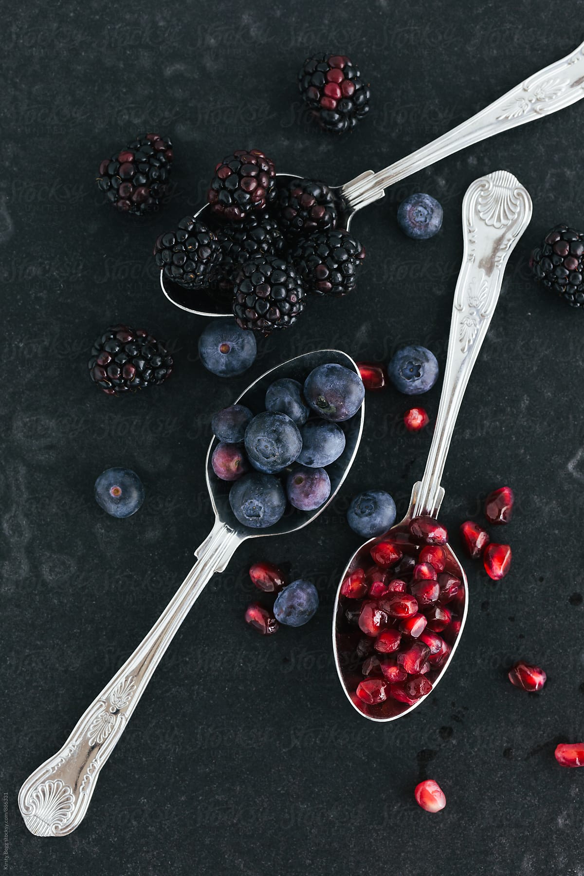 Flat lay of berries and pomegranate seeds in spoons