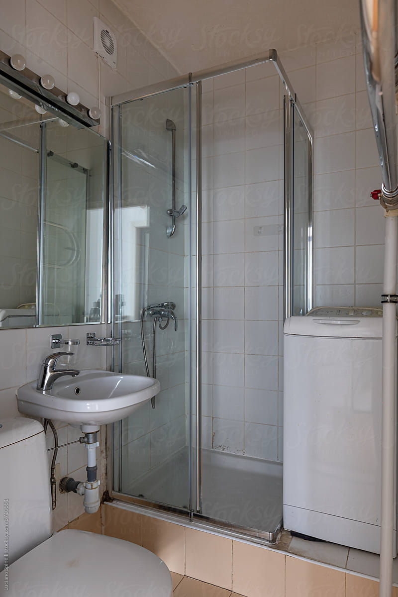 Small studio bathroom with shower, toilet, sink and washing machine
