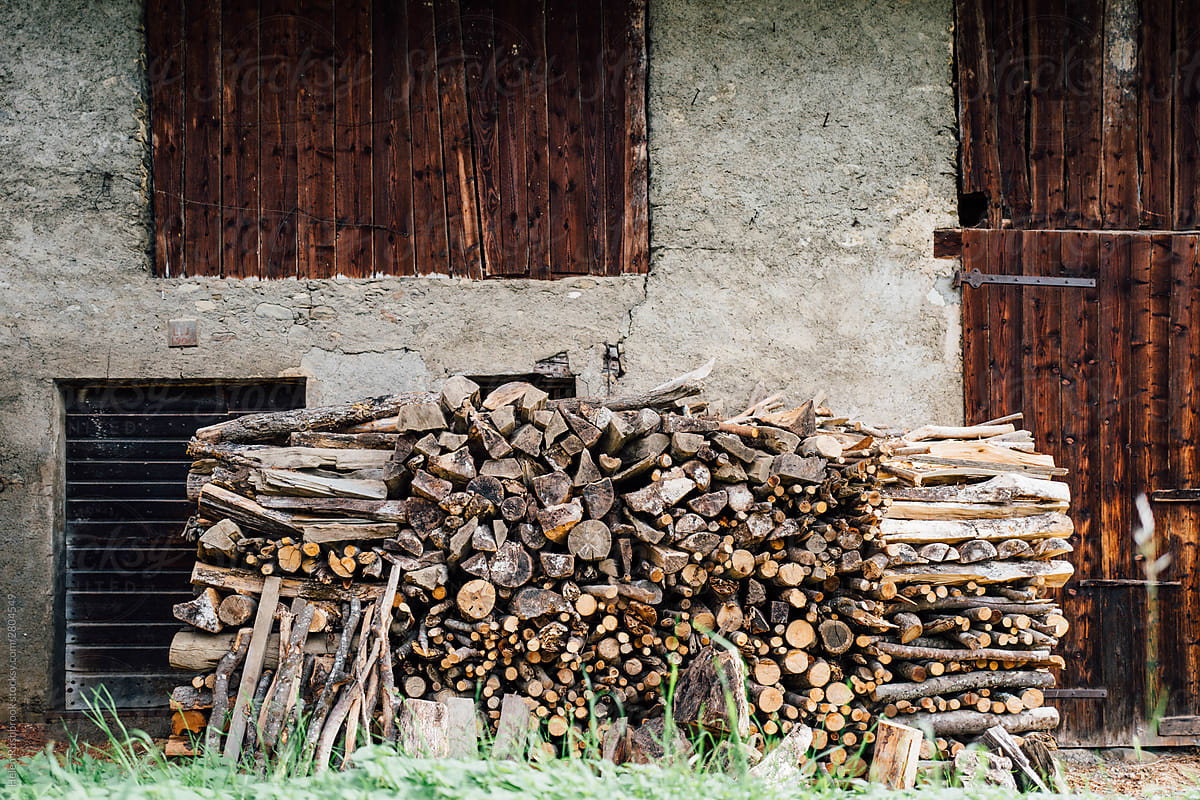 Wood stacked outside a rustic alpine barn.