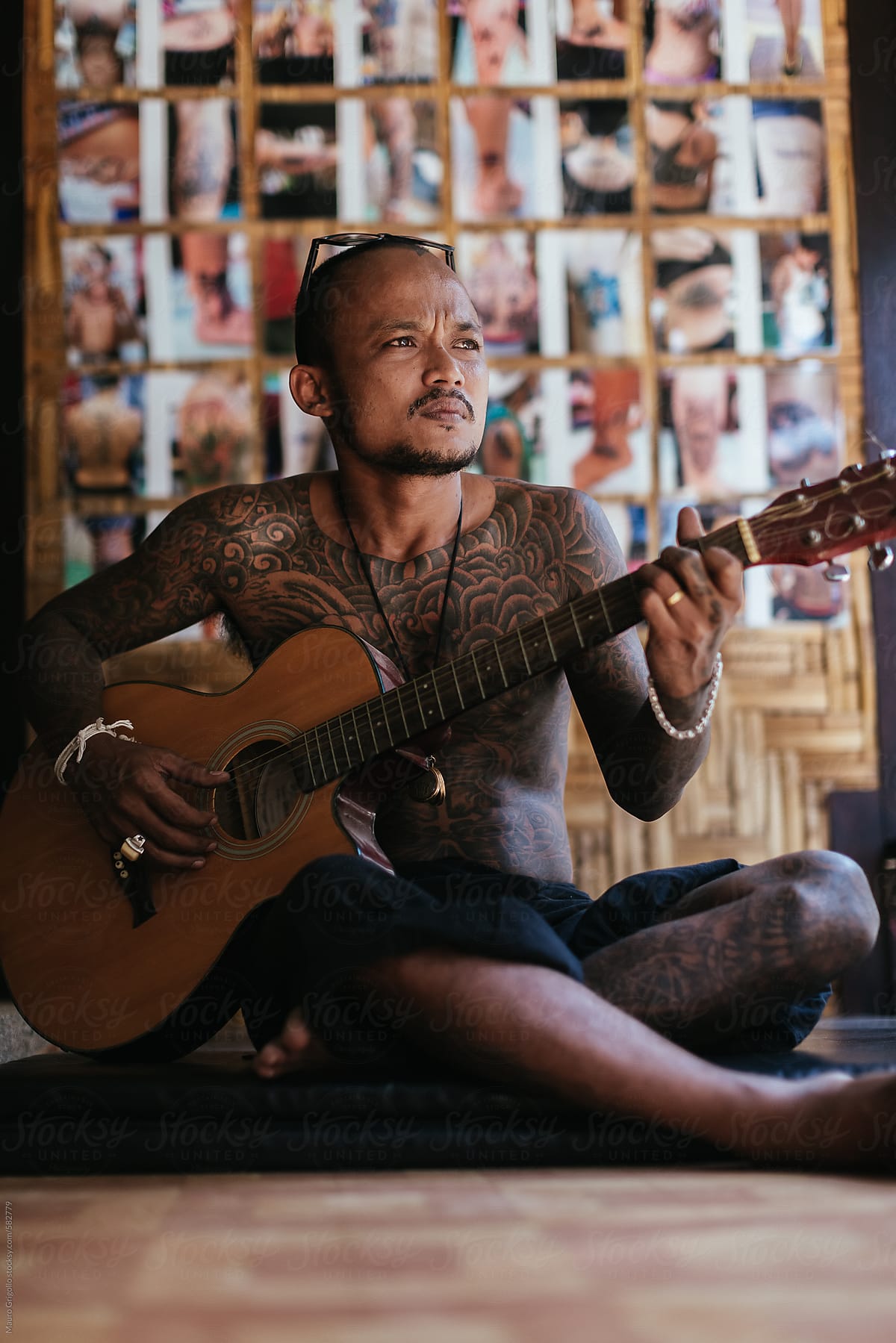 Thai tattoo artist playing guitar during a break.