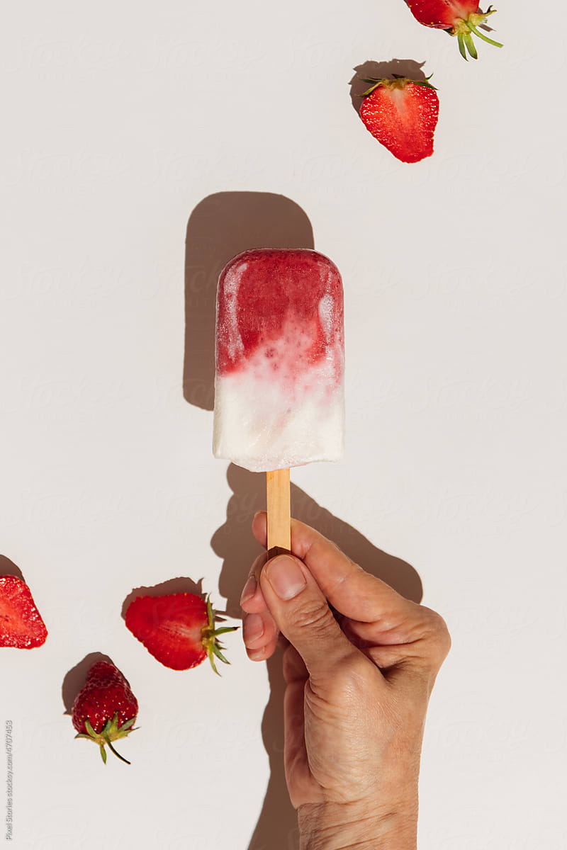 Hand holding homemade strawberry ice cream pops