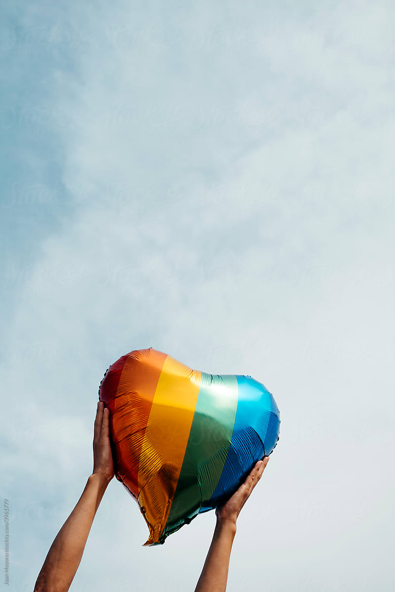 man grabs a rainbow heart-shaped balloon