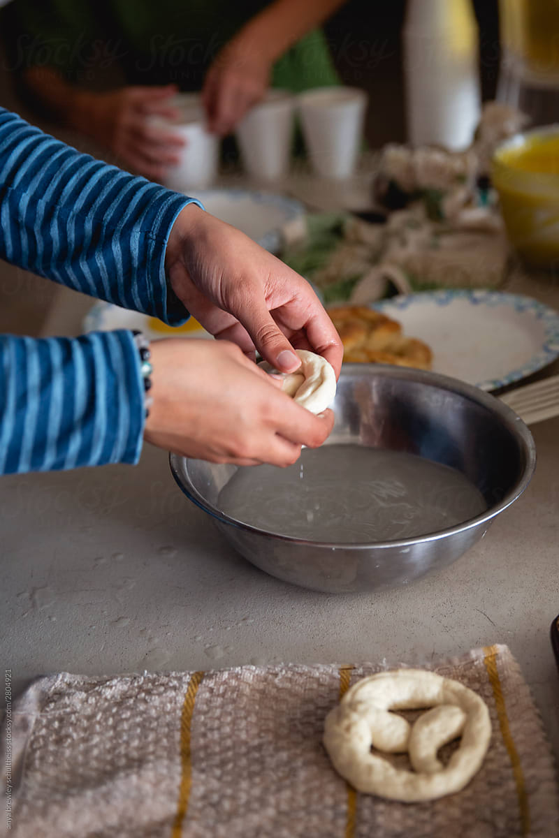 A pair of hands dipping dough into prepared water