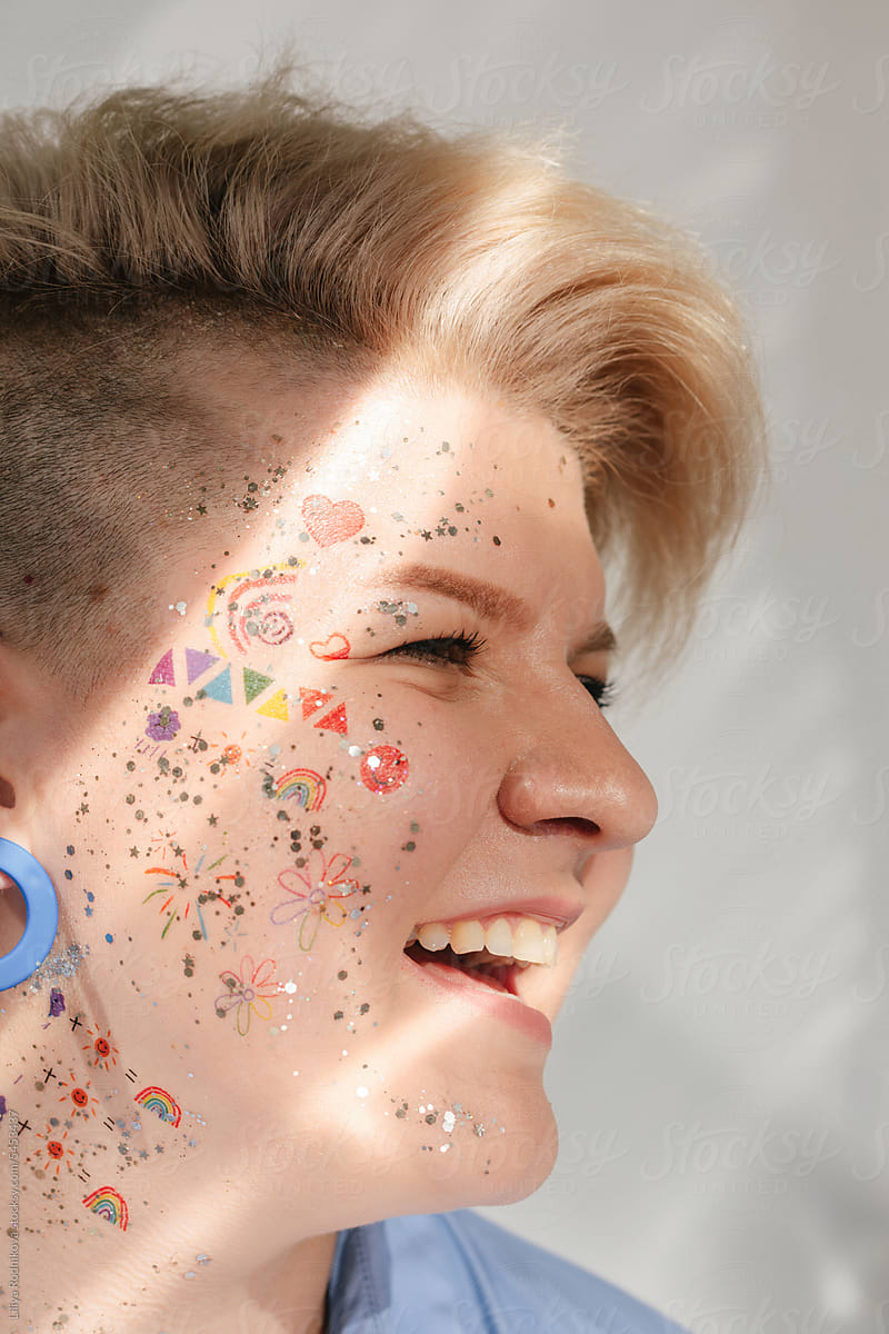 Laughing blond model with shiny face with stickers