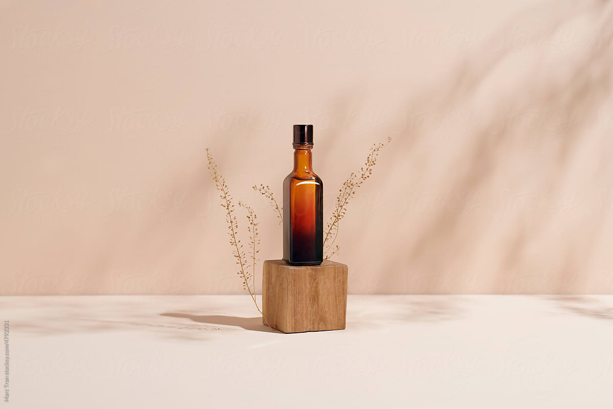 Mock up amber glass bottle on wooden podium on trendy