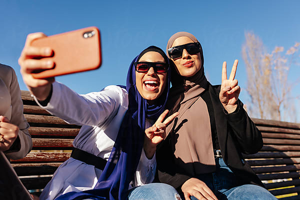 Cheerful Muslim Women In Trendy Clothes And Sunglasses by Stocksy  Contributor VICTOR TORRES - Stocksy