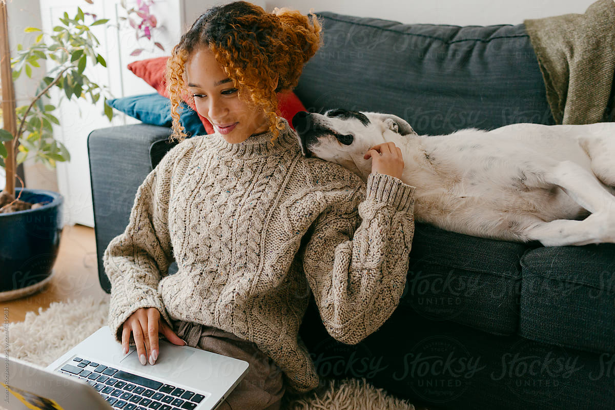 Young woman in cozy outfit at home bonding with dog