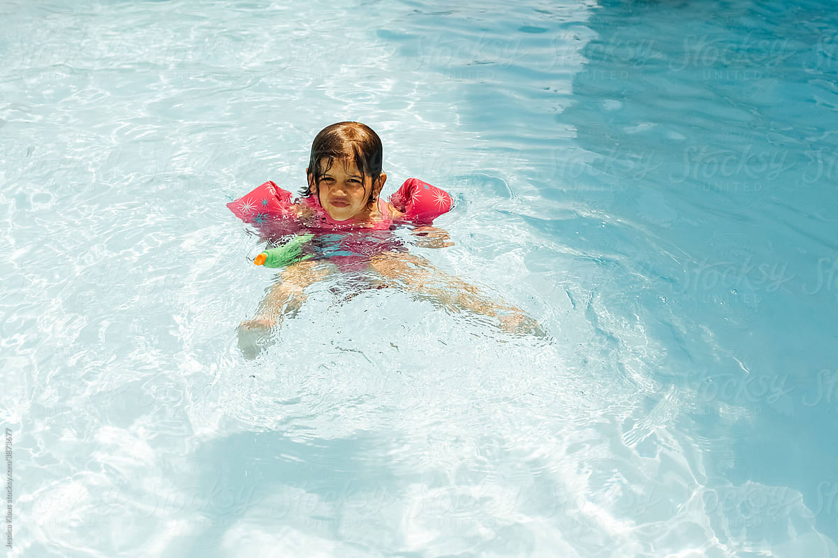 Girl floating in a swimming pool on a summer day.