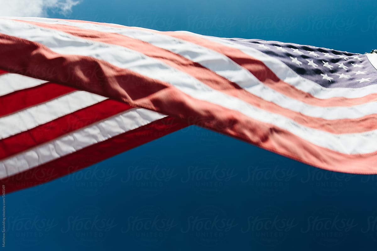 Close up of american flag on waving in wind with blue sky