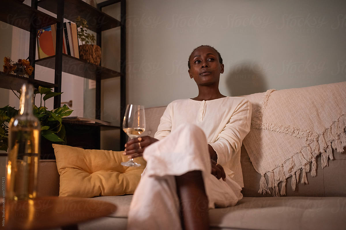 Black woman with wineglass sitting in living room alone