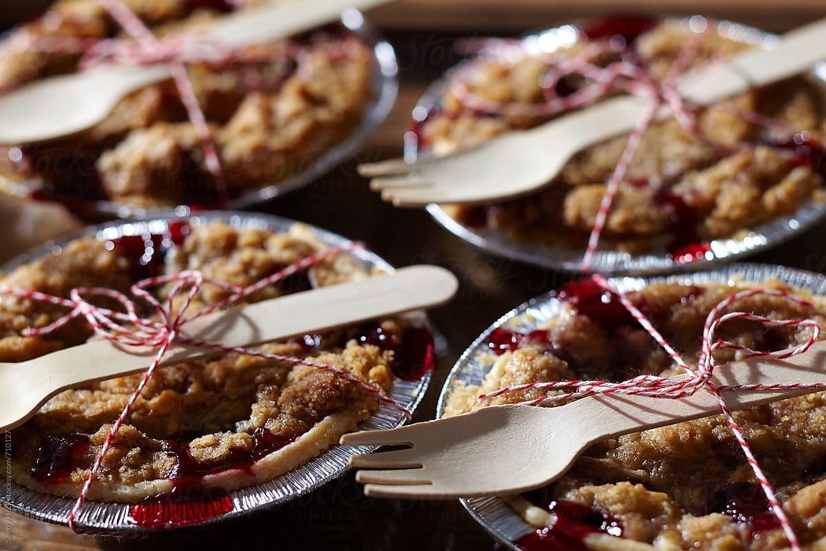 Individual cherry pies in aluminum pie pans with wood forks