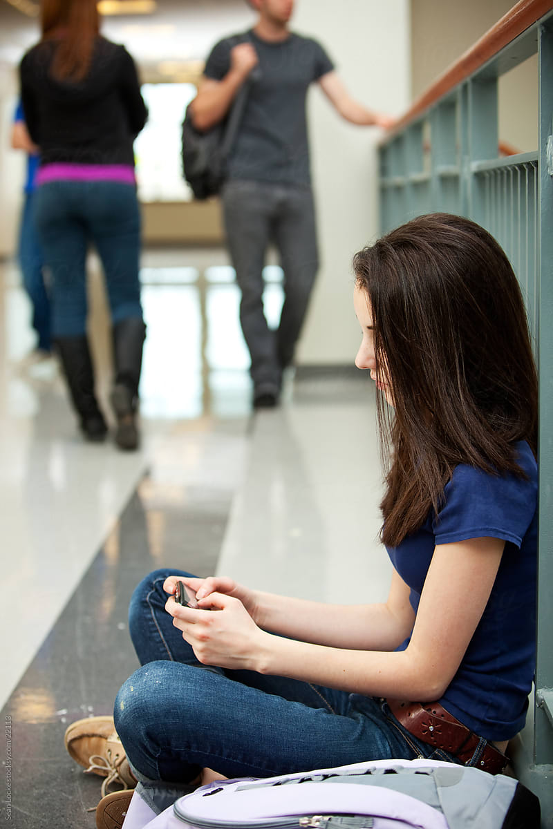 High School: Girl Sits on Floor and Texts in Hallway