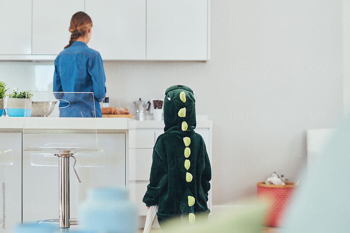 Cute little girl dinosaur asking mom a question in the kitchen of family home