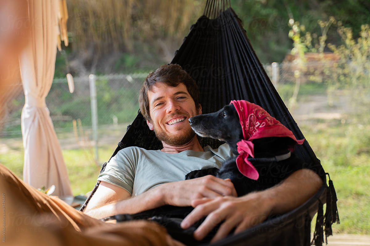 Smiley Man with dog relaxing in hammock
