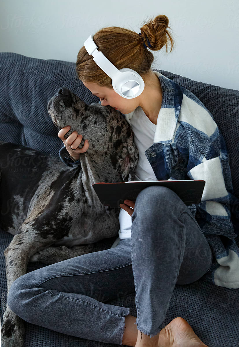 Happy young woman with tablet petting dog