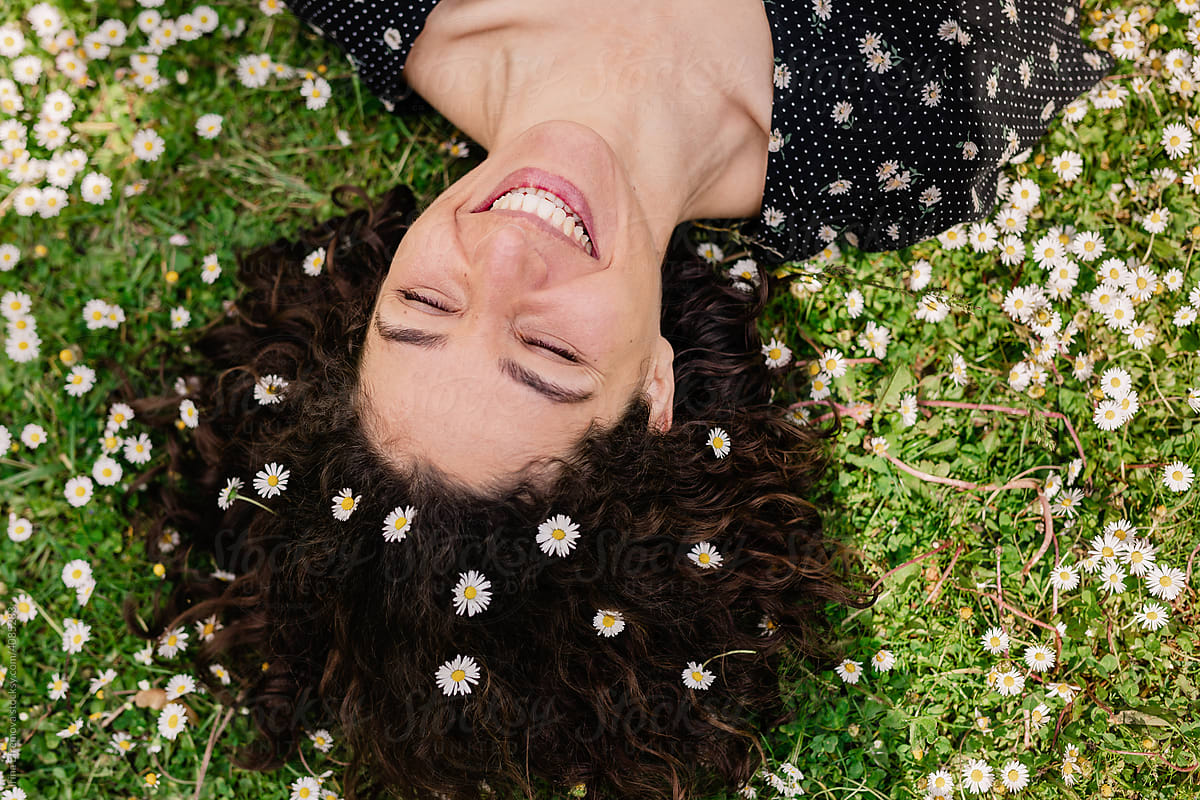 Woman with daisies in her hair laying on the grass