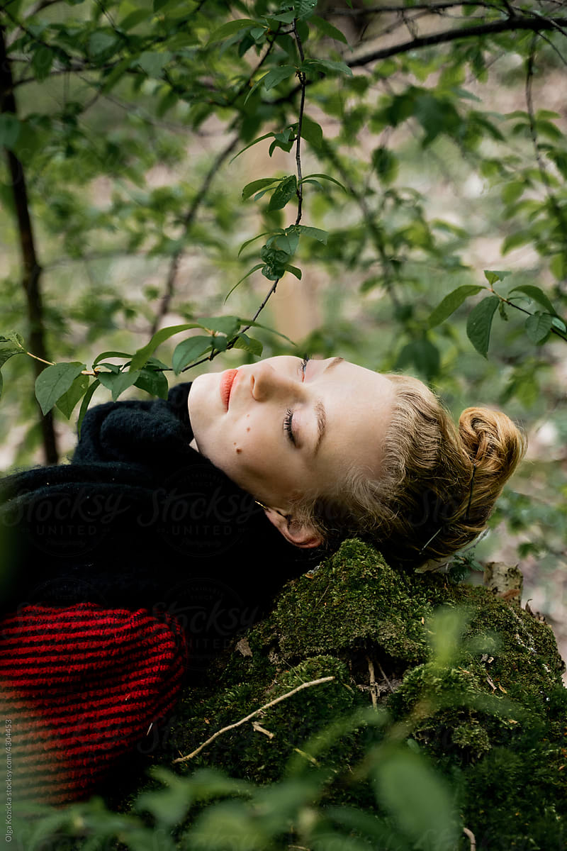 Blonde Woman With Closed Eyes Lying On Rock In Forest